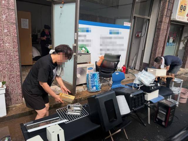 시간당 150㎜ 폭우로 침수 피해를 입은 전북 군산시 나운동의 한 상가 상인이 7일 물에 젖은 집기 등을 밖으로 들어내 말리고 있다. 독자 제공