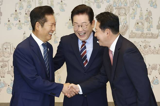 President Lee Jae Myung, center, looks on as Democratic Party leader Jung Chung-rae, left, and People Power Party leader Jang Dong-hyeok shake hands during a luncheon at the presidential office in Yongsan, central Seoul, on Sept. 8. [JOINT PRESS CORPS]