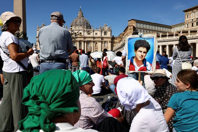 교황 레오 14세가 집전하는 새 성인 카를로 아쿠티스의 시성 미사가 7일 바티칸에서 거행된 가운데 그의 초상화를 건 참가자들이 기도를 하고 있다. 로이터 연합뉴스