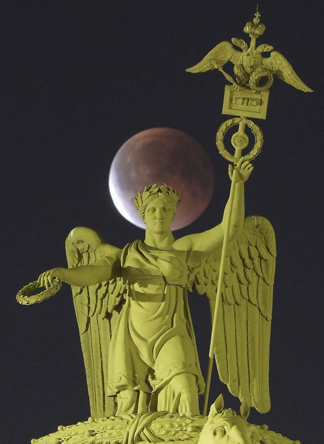 [상트페테르부르크=AP/뉴시스] 7일(현지 시간) 러시아 상트페테르부르크의 궁전광장 내 조형물 뒤 상공에서 개기월식이 진행되고 있다. '개기월식'은 달이 지구 그림자에 완전히 가려지는 천문 현상이다. 2025.09.08.