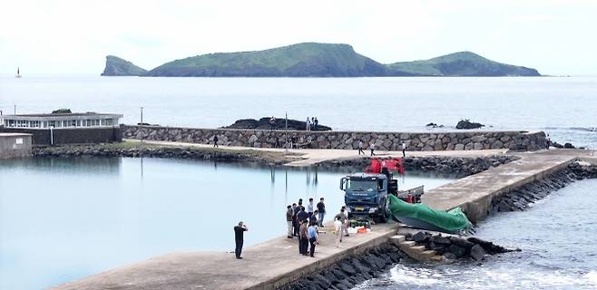 제주 해안서 발견된 정체불명의 보트 - 해경과 경찰 등 관계자들이 8일 오전 제주시 한경면 용수리 해안가에서 이날 오전 발견된 미확인 보트를 조사해 인양하려 하고 있다. 연합뉴스