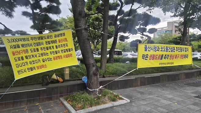 지난 5월부터 울산 남구청 앞 도로에서는 수암로 302번길 도로 개방을 촉구하는 현수막과 장송곡이 반복적으로 울려 퍼지고 있다.