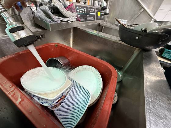 지난 7일 강원 강릉시 한 상인이 설거지 물을 아끼기 위해 고무대야를 사용하고 있다. [연합뉴스]