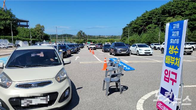 지난 5일 오후 강릉시 스피드스케이팅경기장 주차장에 마련한 '드라이브 스루'를 통해 생수를 받으러 온 차량들이 늘어선 모습. 전영래 기자