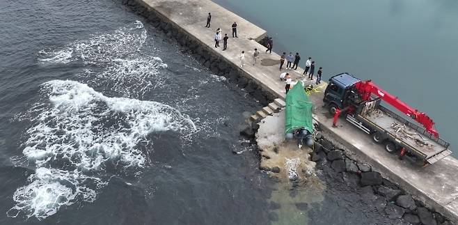 해경과 경찰 등 관계자들이 8일 오전 제주시 한경면 용수리 해안가에서 이날 오전 발견된 미확인 보트를 조사해 인양하려 하고 있다. 해당 보트는 중국인 밀입국자들이 탔던 것으로 확인됐다. 연합뉴스