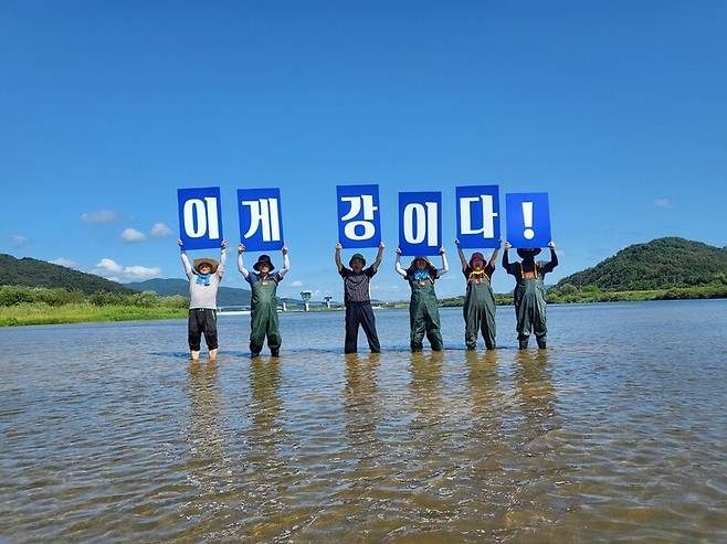 지난 5일 환경운동가들이 감천과 낙동강 합류부의 맑은 모래강에 들어가 ‘이게 강이다!’ 피켓을 들고 있다. 환경운동연합 제공