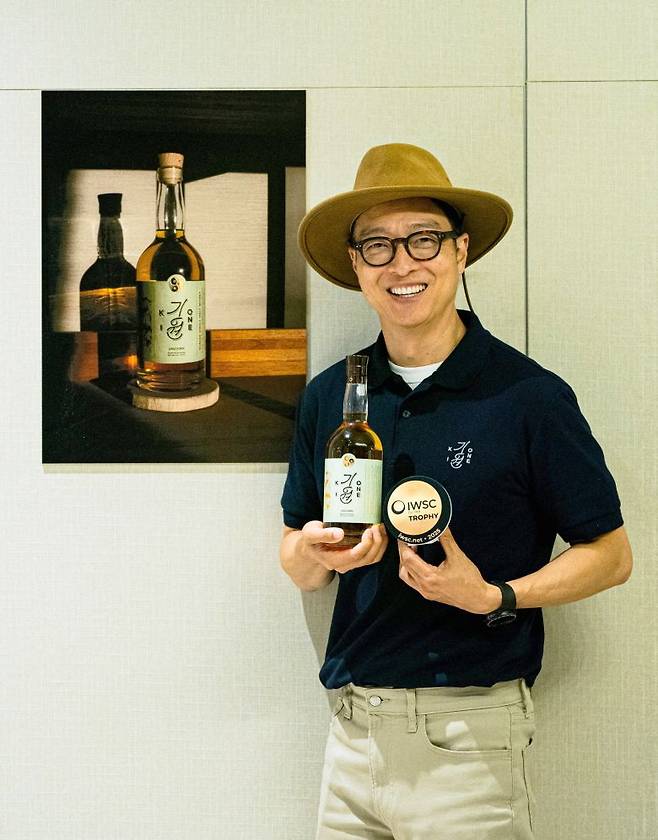 도정한 기원 위스키 대표가 국제 와인 & 스피릿 대회(IWSC) 수상 트로피와 위스키를 들고 포즈를 취하고 있다. 기원 제공