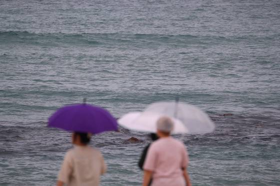 12일 강원 강릉시 강문해변에 약한 비가 내리며 시민들이 우산을 쓰고 걷고 있다. 연합뉴스