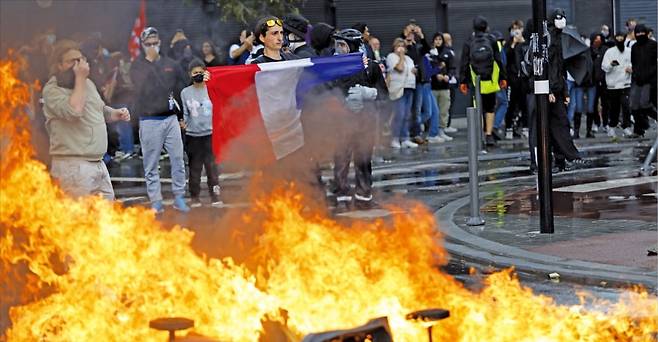 프랑스에서 ‘국가 마비’ 운동이 벌어진 가운데 10일(현지시간) 북부 도시 릴의 거리에서 한 남성이 프랑스 국기를 들고 시위하고 있다.   /AP연합뉴스