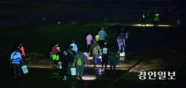 지난달 22일 오후 인천시 옹진군 영흥면 내리에서 늦은 밤 해루질을 하기 위해 모인 동호인들이 어촌계 어장 진입로를 이용해 갯벌로 들어가고 있다. 2025.8.22 /조재현기자 jhc@kyeongin.com