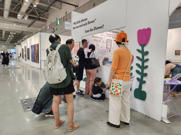 창원 사는 아인이네 가족이 13일 창원컨벤션센터에서 열리는 '제12회 경남국제아트페어'를 찾았다. 아인이가 예술 체험 공간인 키즈 라운지&아트 플레이존에서 색칠하는 가운데 가족들이 바라보고 있다. /류민기 기자