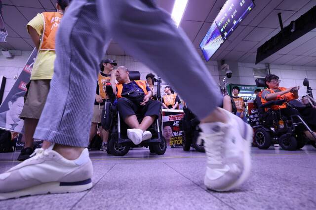 전국장애인차별철폐연대 회원들이 지난달 26일 오후 서울지하철 1호선 시청역 승강장에서 오세훈 서울시장에 대화를 촉구하는 ‘15차 12345 지하철행동’ 시위를 하고 있다. 시위하는 이들 앞으로 시민이 지나가고 있다. 최현수 기자 emd@hani.co.kr