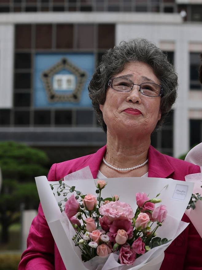 최말자씨가 2025년 9월10일 오후 부산 연제구 부산지방법원에서 열린 재심 선고공판에서 무죄를 받은 뒤 법원 앞에서 꽃다발을 받고 감개무량한 표정을 짓고 있다. 부산=이종근 선임기자 root2@hani.co.kr