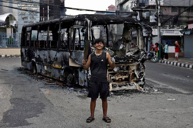 지난 10일 네팔 카트만두에서 시위에 참여한 18세 학생 카란 쿨룽이 시위 후에 진행된 청소 캠페인에 참여하며 불타버린 버스 앞에서 사진을 찍고 있다. 카란 쿨룽은 “처음엔 여기서는 미래가 없다고 생각해 기회를 찾아 해외로 나가려 했지만 지금 제 목표는 네팔을 발전시키고 이곳에서 더 나은 미래를 만드는 데 기여하는 것입니다”라고 말했다. 로이터연합뉴스