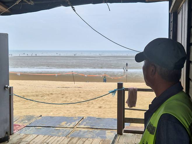 ▲&nbsp;16일 오전 인천 중구 무의도 하나개해수욕장에서 만난 포내어촌계원 A씨가 이곳을 방문한 관광객을 바라보고 있다./ 안지섭 기자 ajs@incheonilbo.com