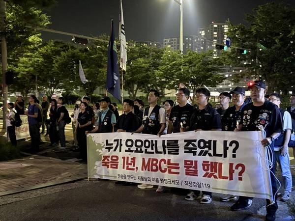 ▲추모제 말미에는 '누가 오요안나를 죽였나? 죽음 1년, MBC는 뭘 했나?'라고 적힌 현수막을 든 시민들이 약 30분 동안 MBC 사옥을 한 바퀴 행진했다. 시민들은 MBC 사옥 앞을 지키고 있는 MBC 직원들과 경찰들을 향해 구호를 외쳤다. 사진=윤유경 기자.