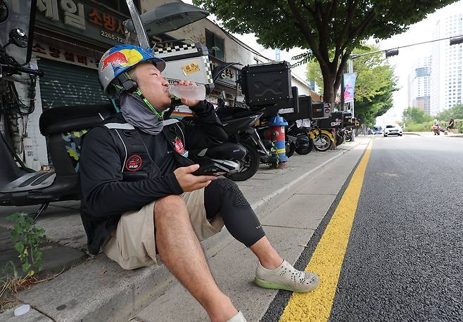 서울 시내에서 한 배달 노동자가 물을 마시며 더위를 식히고 있다.[연합]