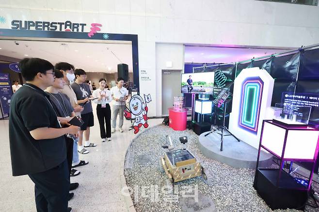 슈퍼스타트 데이 2025에서 LG 직원들이 LG의 카메라 모듈, 배터리 셀, 통신 모듈용 안테나가 탑재된 무인탐사연구소의 달 탐사 로버에 대한 설명을 듣고있다. (사진=LG)