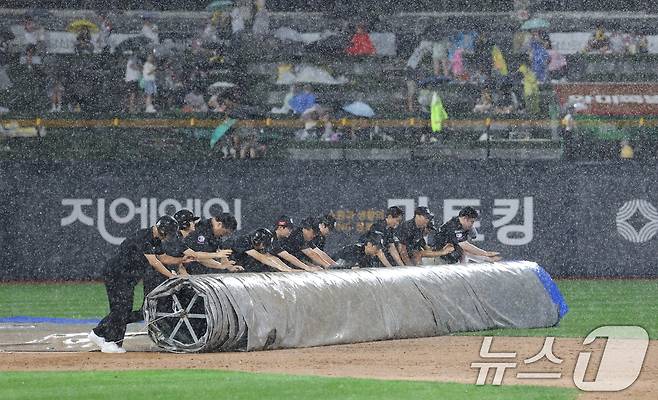16일 오후 경기 수원시 장안구 KT위즈파크에서 열린 '2025 신한 SOL 뱅크 KBO리그' LG 트윈스와 KT 위즈의 경기, 3회말 우천으로 경기가 중단돼 구단 관계자가 방수포를 덮고 있다. 2025.9.16/뉴스1 ⓒ News1 김영운 기자