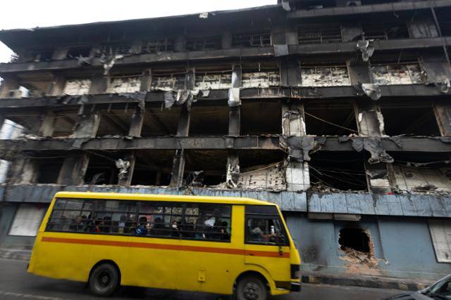 15일 네팔 카트만두에서 스쿨버스가 화재로 전소한 대형 유통 체인 바트바테니 매장 앞을 지나고 있다. 카트만두=EPA 연합뉴스