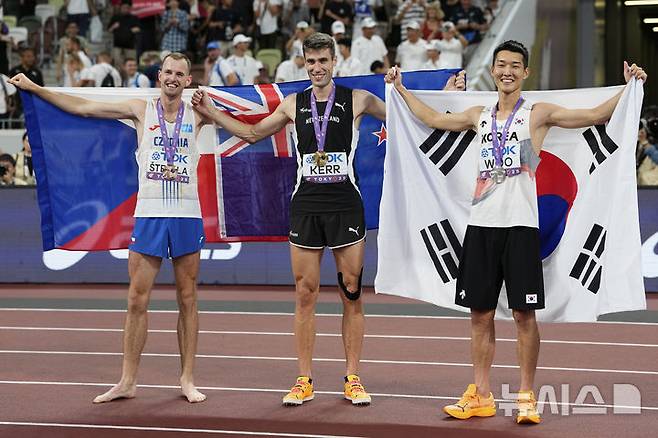 [도쿄=AP/뉴시스] 우상혁(오른쪽)이 16일 일본 도쿄 국립경기장에서 열린 2025 도쿄 세계육상선수권대회 남자 높이뛰기 결선에서 2ｍ34로 은메달을 획득한 뒤 금메달의 해미시 커(뉴질랜드, 가운데), 동메달의 얀 스테펠라(체코)와 포즈를 취하고 있다. 2025.09.16.