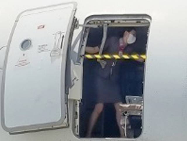 지난 26일 오후 제주공항에서 출발해 대구공항에 비상구 출입문이 열린 채 착륙한 아시아나항공기에서 한 승무원이 문에 안전바를 설치한 뒤 두 팔을 벌려 막고 있다. 연합뉴스