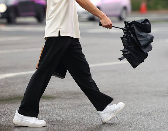 서울 광화문사거리에서 한 시민이 우산을 접어 들고 횡단보도를 건너고 있다. 2025.8.26 [사진=연합뉴스]