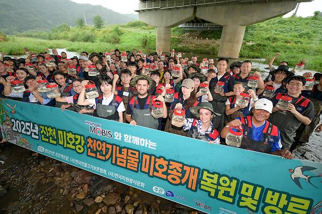 현대모비스 국내외 임직원들이 지난 17일 충북 진천 미호강 일대에서 멸종위기종인 미호종개 치어 방류 행사에 참여한 뒤 기념 촬영을 하고 있다. 현대모비스 제공