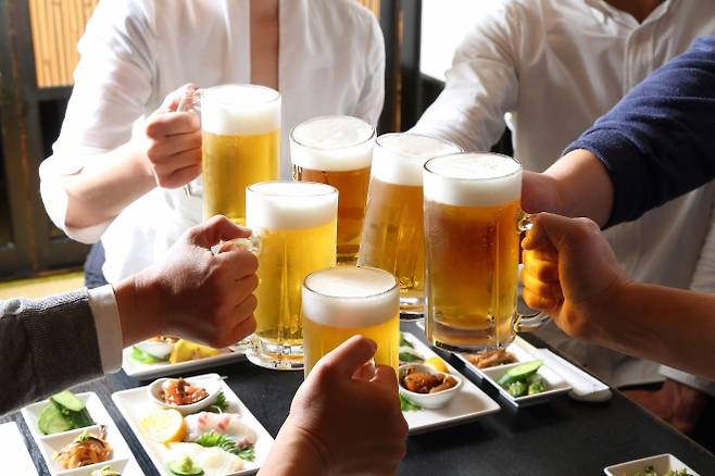 사람들이 술자리를 즐기며 맥주를 마시고 있다. 전문가들은 인간에게는 소량의 음주도 건강 위험을 높일 수 있다고 경고한다. 123rf