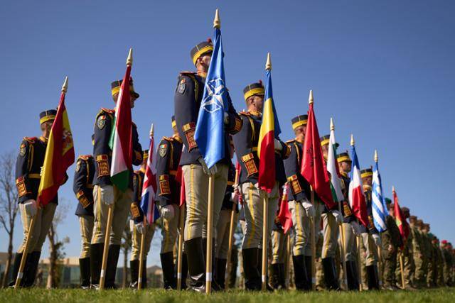 루마니아 부쿠레슈티에서 19일 북대서양조약기구(NATO·나토) 남동부 본부 설립 10주년을 기념하는 행사가 열린 가운데, 경비연대 대원들이 나토 국가 국기를 들고 있다. 부쿠레슈티=AP 연합뉴스