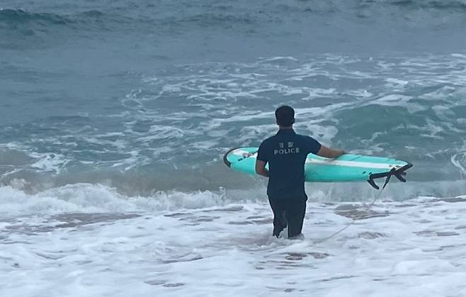 오늘(20일) 오전 중문색달해수욕장에서 물에 빠진 관광객을 보고 서핑 보드를 들고 구조에 나선 김양재 경사 (제주경찰청 제공)