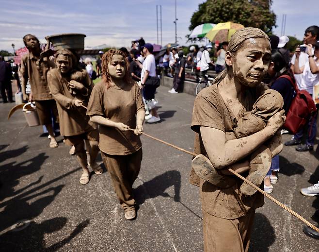 “홍수 피해자를 기억하라” 필리핀 청년들이 21일 진흙으로 몸을 뒤덮은 채 홍수 대비 기반시설 공공사업 비리 스캔들에 항의하는 시위를 하고 있다. EPA연합뉴스