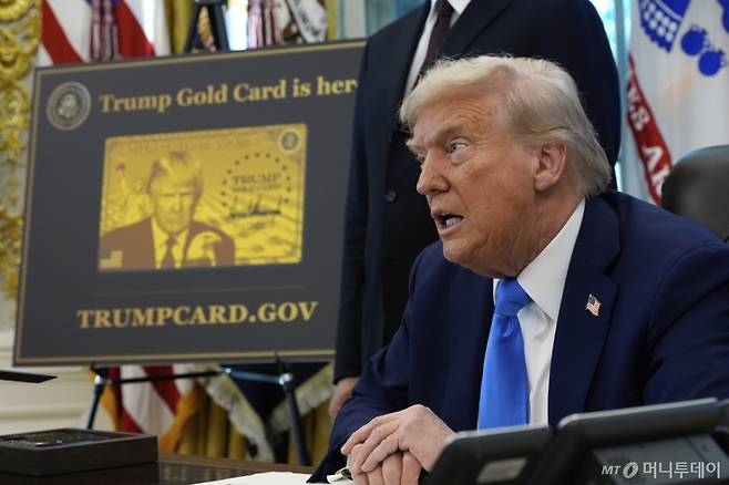 [워싱턴=AP/뉴시스] 도널드 트럼프 미국 대통령이 19일(현지 시간) 백악관 집무실에서 골드 카드 관련 행정명령에 서명하는 가운데 '트럼프 골드 카드' 포스터가 옆에 진열돼 있다. 백악관 측은 이 행정명령이 "미국에 진정으로 이바지할, 탁월한 인재들을 위한 새로운 길을 열어줄 것"이라고 설명했다. 2025.09.20. /사진=민경찬