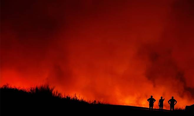 지난 8월 11일(현지시간) 스페인 푸에르카스에서 산불이 타오르는 가운데 사람들이 실루엣으로 보인다. 로이터연합뉴스
