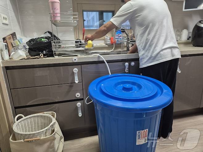 강원 강릉지역 저수조 용량 100톤 이상 아파트 113곳에 대한 시간제 제한급수가 풀린 지난 19일 저녁 강릉 회산동의 한 아파트 주민이 수돗물을 이용해 설거지를 하고 있다. 싱크대 근처에 그동안 물을 아끼려고 달아놓은 샤워헤더와 물통이 놓여 있다.2025.9.19/뉴스1 ⓒ News1 윤왕근 기자