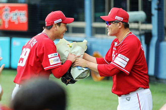 SSG 김광현(왼쪽)이 잠실구장에서 열린 2025 KBO리그 LG전에서 3회까지 삼진 3개 뽑아내며 통산 2000삼진 고지를 밟았다. 더그아웃으로 돌아오는 김광현에게 이숭용 감독이 꽃다발을 건네며 축하하고 있다. 사진 | SSG 랜더스