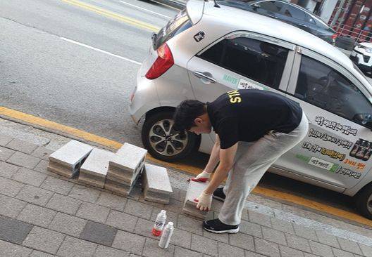 이수열씨가 피트니스센터 2호점 홍보를 위해 벽돌에 로고를 그리고 있다.