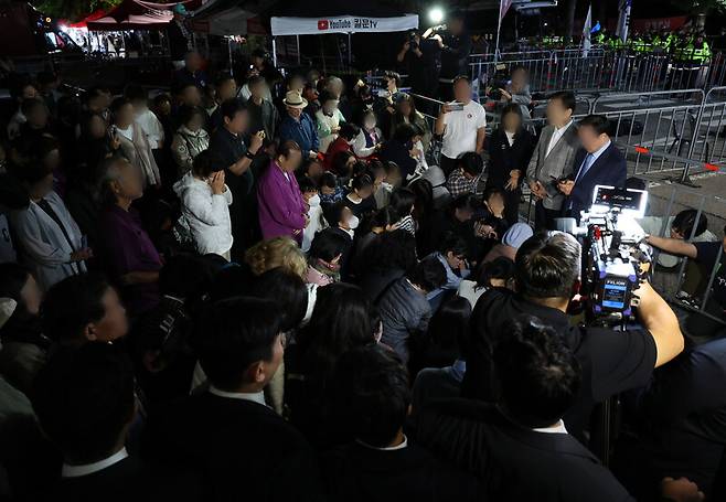 윤석열 정권과 통일교 간 ‘정교유착 국정농단’ 의혹을 받는 한학자 통일교 총재가 23일 새벽 구속되자 경기도 의왕 서울구치소 앞에서 이를 지켜보던 신도들이 통일교 측의 입장 발표를 듣고 있다. 연합뉴스