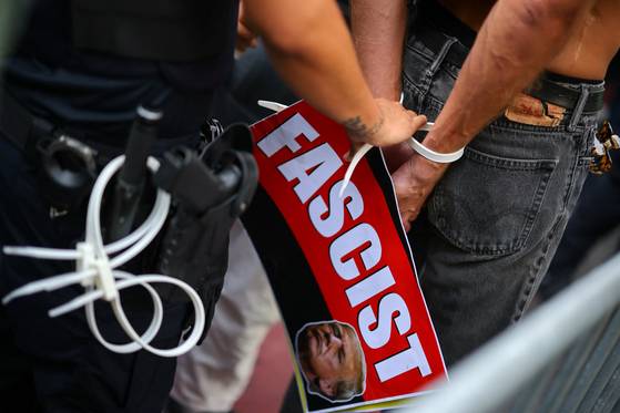 23일(현지시간) 미국 뉴욕 유엔본부에서 열린 제80차 유엔총회 인근 시위에서 경찰이 도널드 트럼프 미국 대통령을 묘사한 플래카드를 든 시위자의 손을 묶고 있다. 로이터=연합뉴스