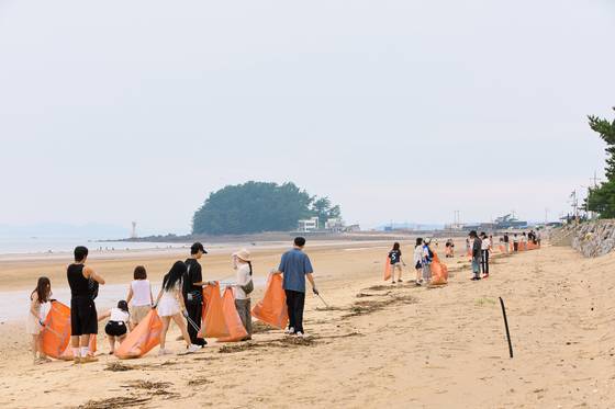 2030세대가 주축인 봉사단체 ‘FPP’ 회원 50여 명이 지난달 9일 충남 태안군 해변에서 지역 주민들과 함께 모래사장을 걸으며 쓰레기도 줍는 ‘플로깅’ 행사를 진행하고 있다. 원동욱 기자
