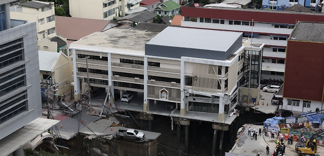 24일 태국 방콕 두싯 지역에서 도로 붕괴로 대형 싱크홀이 발생해 차량이 추락하고 병원·경찰서 건물이 붕괴 위험에 놓였다.로이터=연합뉴스