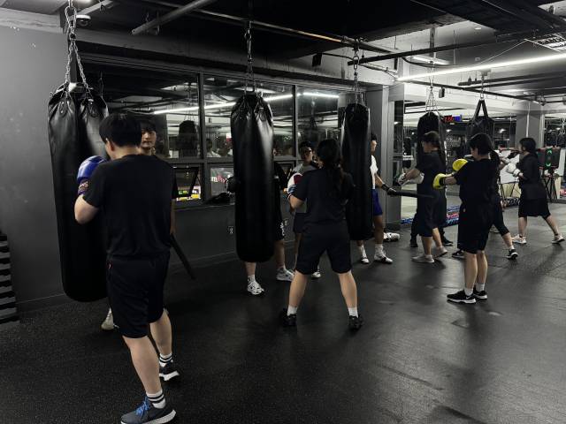 복싱장 관원들이 샌드백을 치고 있다.
