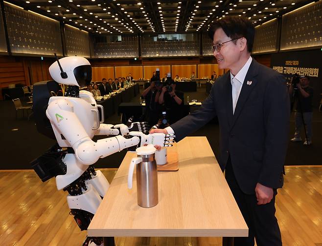25일 서울 중구 대한상공회의소에서 열린 '2025년 제3차 산업융합 규제특례심의위원회'에서 김정관 산업통상자원부 장관이 휴머노이드 로봇과 악수하고 있다.  연합뉴스