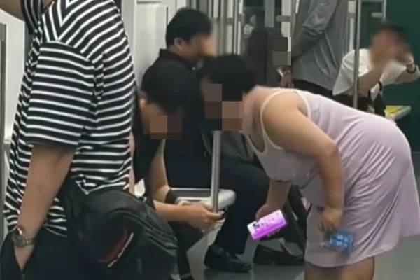 지하철 2호선 성수역 부근 열차 안에서 한 여성이 자리에 앉아 있는 남성 승객에게 얼굴을 들이밀고 풍선껌을 불고 있다. [보배드림 갈무리]