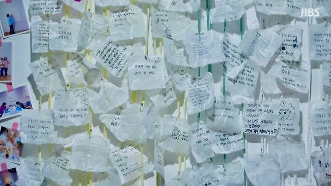 전시장 벽면을 가득 메운 손글씨 쪽지. 익명의 메시지가 또 하나의 이불이 되어 마음을 덮는다.