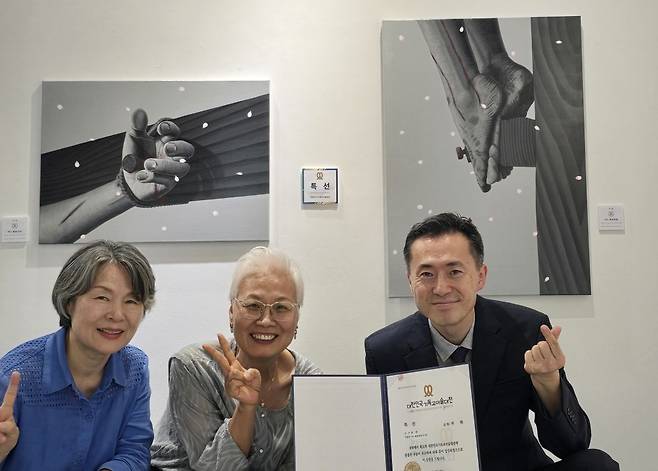 빛교회 양태우(맨 오른쪽) 목사와 방영옥(가운데) 작가, 이강녀 권사가 최근 열린 대한민국기독교미술대전 시상식에서 특선을 수상한 무기수 김철수(가명)씨의 그림 앞에서 웃고 있다. 이들은 서울 여러 구치소에서 다양한 봉사를 하고 있다. 방 작가 제공