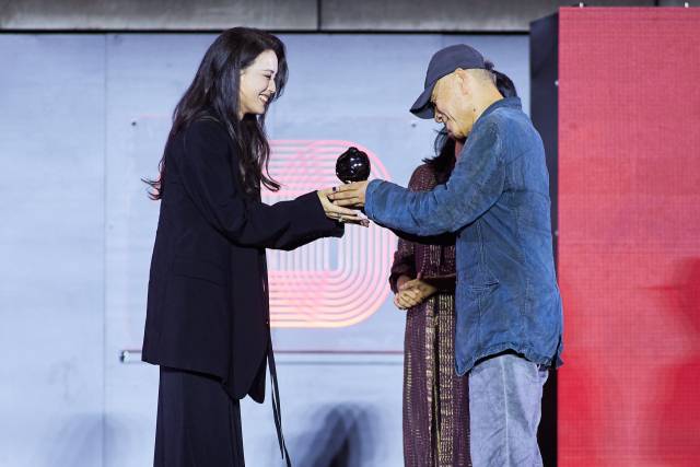 지난 26일 오후 부산 해운대구 영화의전당 야외무대에서 열린 제30회 부산국제영화제 폐막식에서 첫 연출작 '소녀'로 경쟁부문 '부산 어워드' 감독상 주인공이 된 서기가 장선우 감독으로부터 트로피를 받고 있다. BIFF 제공