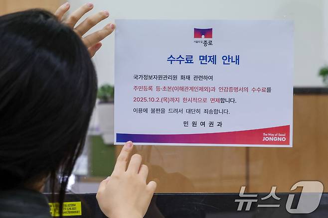 정부가 대전 국가정보자원관리원(국정자원) 전산실에서 발생한 화재로 중단된 행정정보시스템 복구에 총력을 기울이고 있는 29일 오전 서울 종로구청에서 직원이 주민등록 등·초본과 인감증명서 수수료 한시적 면제 안내문을 부착하고 있다. 2025.9.29/뉴스1 ⓒ News1 안은나 기자