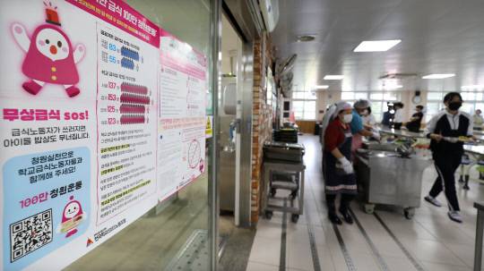 조리원들의 무기한 파업이 시작된 30일 대전 서구 둔산여자고등학교 급식실에 학교비정규직노조의 '무상급식 SOS' 안내문이 붙어 있다. 안쪽에서는 교직원과 남은 조리원이 급식을 배식하고 있다.  김영태 기자