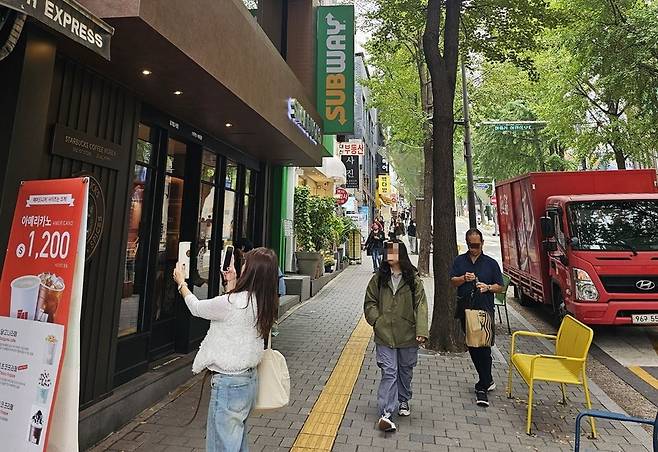 30일 서대문구 대현동 국내 스타벅스 1호점 앞에서 한 시민이 기념품을 구입한 뒤 기념사진을 찍고 있다.
